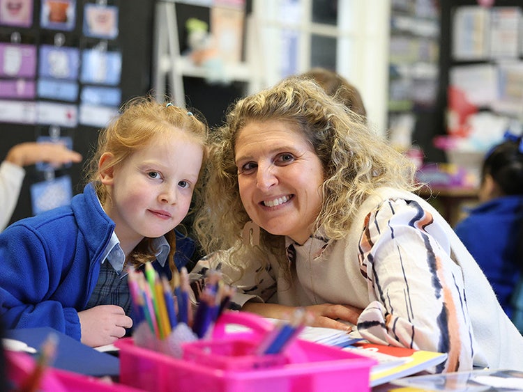 A mother and child in the classroom, smiling.