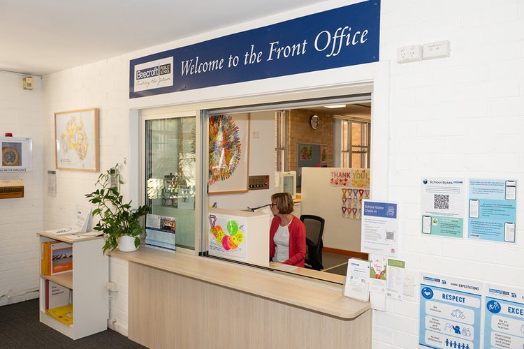 view of a school front office from the foyer looking into the main window where the receptionist sits.